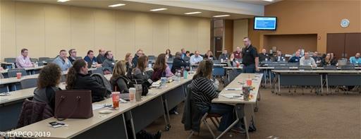 Man walking down the middle of the two rows of tables.